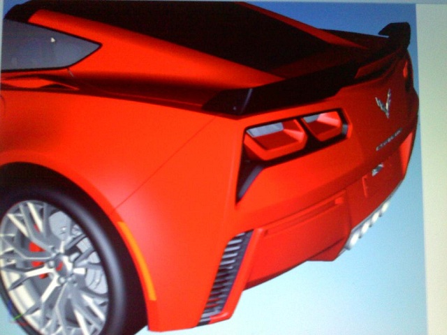 Back End Of The C7 Corvette?  - Page 1 - Corvettes - PistonHeads - This image shows a photograph of a sleek red Chevrolet Corvette C8 sports car from a rear three-quarter perspective. It displays the distinctive rear design of the Corvette, with its angular taillights and the iconic bowtie emblem. The car is styled with a smooth and aerodynamic body, featuring a vented rear spoiler, black winged mirror caps, and five-spoke alloy wheels. The setting appears to be a controlled environment, possibly a showroom or studio, due to the plain background.