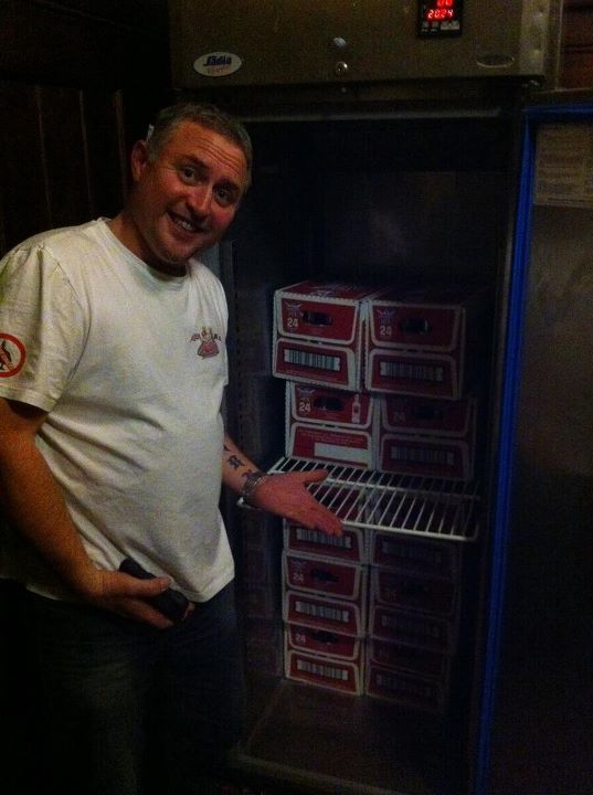 Pistonheads - The image captures a cheerful moment inside a store where a man is casually leaning against a refrigerator. He is dressed in a simple white t-shirt and jeans, exuding an air of casual comfort. Before him, the refrigerator holds a neatly stacked set of six beer kegs, their vibrant red and tan colors standing out against the cooler's interior. The man is holding up a small phone, perhaps showing a photo related to the scene or capturing the moment. The overall setting suggests a relaxed and informal atmosphere, possibly in a bar or convenience store where beer is a popular item.