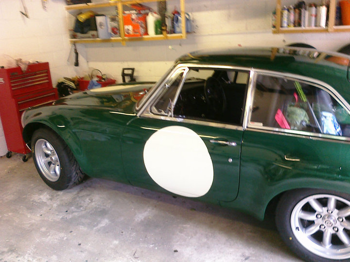 Mgb Modification Pistonheads - The image depicts a classic, green sports car, likely a Lotus Elan, parked inside a garage. The vehicle has a distinctive round club louise indicator. The interior of the garage is visible with various tools and equipment stored on shelves and a red workbench. The overall atmosphere suggests a love for automotive restoration and maintenance.