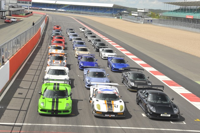 A group of buses parked in a parking lot - Pistonheads - The image captures an exciting scene from a circuit race. A multitude of colorful cars, each uniquely configured with different designs and modifications, are zooming around a curved track. The cars are fiercely competing in a track race, adding a sense of speed and dynamism to the scene. The trucks, scattered around the area, appear to be supporting vehicles used for track service or transportation of racing equipment. The layout of the track and its surroundings provide a structured and organized environment, typical of a professional racing circuit.