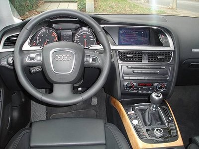 What car does this interior belong to? - Page 1 - General Gassing - PistonHeads - This image captures the interior of a vehicle, focusing on the cockpit. A steering wheel is positioned in the center, with a dashboard that has multiple gauges and a touchscreen display. The gear stick of an automatic transmission is clearly visible on the center console, along with several buttons that could be for the climate control system and other vehicle functions. The dashboard is dotted with several air vents, and the car's upholstery appears to be made of leather, indicative of a premium vehicle.