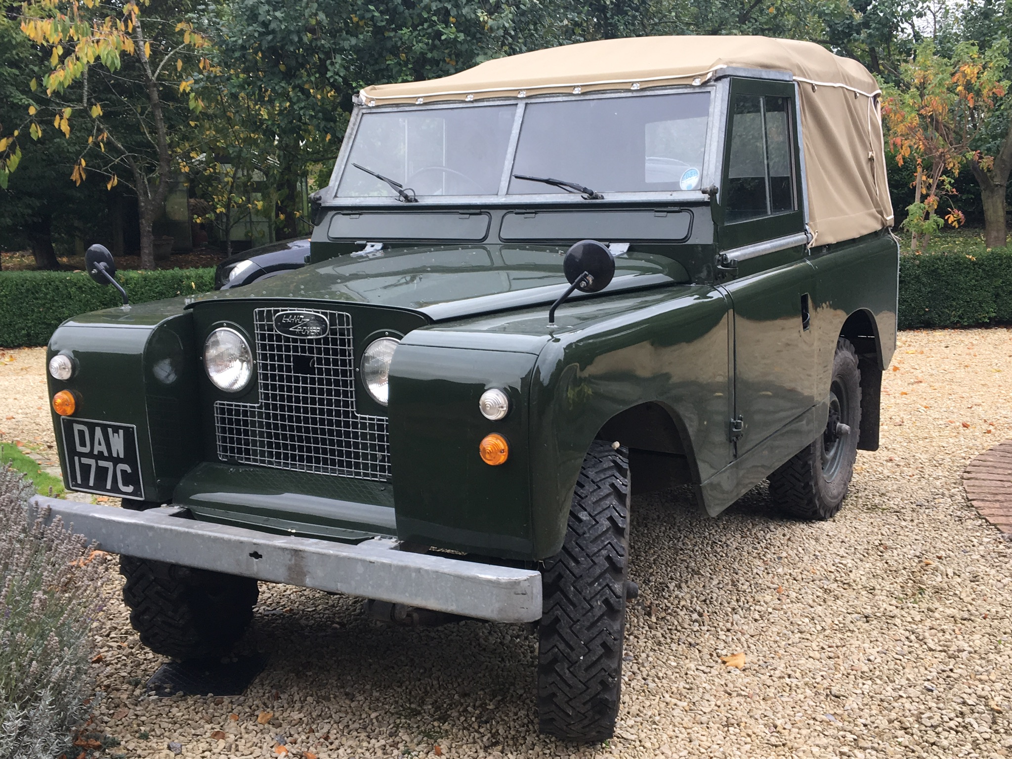 RE: Defender makes UK debut at Goodwood Revival... - Page 1 - General Gassing - PistonHeads - The image shows an old, green Land Rover parked on a paved area. It appears to be in good condition with no visible damage. There's a canvas cover or tarp covering the back of the vehicle. The license plate is not visible due to the angle and resolution of the photo. The setting suggests it might be autumn, as indicated by the presence of fallen leaves on the ground around the vehicle.