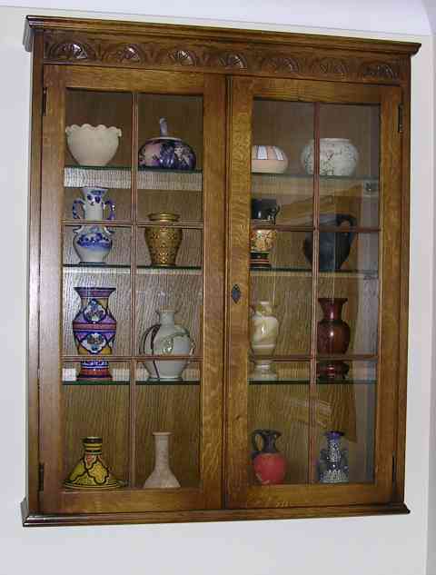 Pistonheads - The image features a wooden china cabinet displaying a variety of ceramic vases. In the top shelves, there are white and colorful decorative items. The middle and lower shelves are filled with jars in various shapes and sizes, primarily in earthy and pastel tones. The cabinet has simple, light-colored decorations near the top. The cabinet closure also shows interesting patterns and designs, contributing to an overall vintage aesthetic.