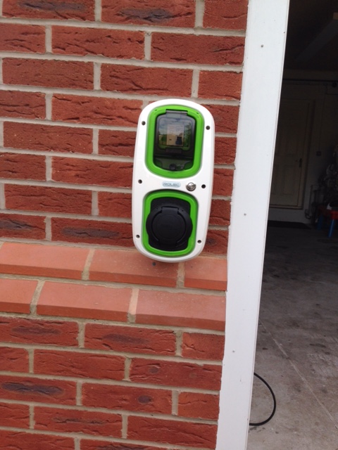 A close up of a mirror on a wall - Pistonheads - The image showcases a modern, sleek, double-colored smart meter that is affixed to the wall of a brick building. The smart meter features a mixture of white and green colors. It has a large touch screen display at the center, which is glowing with some green and black graphics. The wall on which the smart meter is mounted appears to be a red brick wall with a smooth finish. The handheld device is positioned in such a way that it is easily accessible to anyone approaching the building.