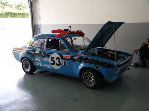 Sepang Afos Pistonheads - The image showcases a blue vintage vehicle parked inside a garage. The car is the most prominent object in the image, occupying a significant portion of the frame. It features a striking black and white number "53" prominently displayed. The car is opened up to display various parts, suggesting that it might be undergoing modification or restoration. A single person can be seen in the background, adding a human element to the otherwise mechanical setting.