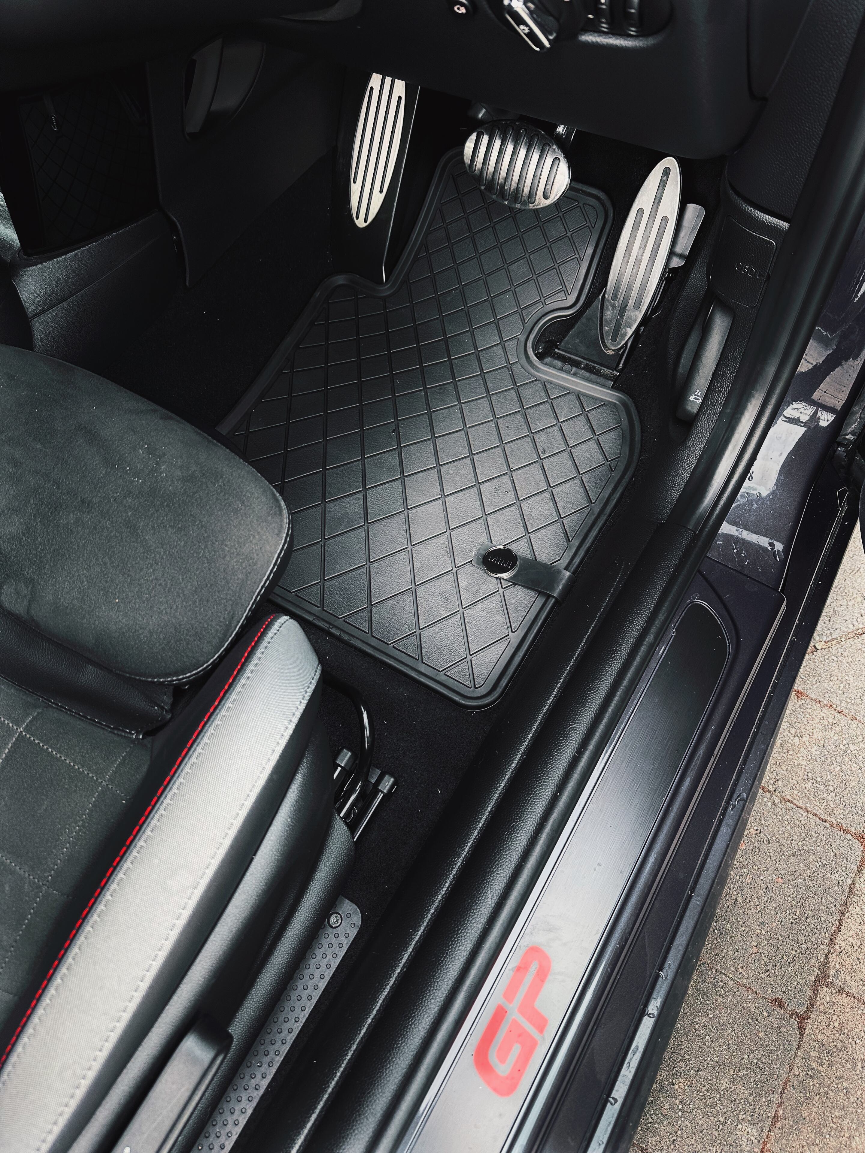 Pistonheads - The image displays the interior of a vehicle, specifically focusing on the front passenger side. There is a sports car seat visible, with red and black accents, suggesting a high-performance theme. A gear shift knob is prominently positioned within easy reach, indicating the car's manual transmission system. The floor mats feature a distinctive checkered pattern, adding to the sporty aesthetic of the vehicle. The overall design and elements suggest a customized or tuned vehicle, possibly used for racing or performance driving.