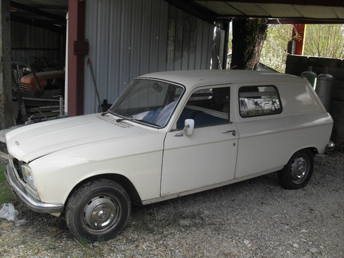 304 fourgon... - Page 1 - French Bred - PistonHeads - The image shows a white vintage car parked partially inside a metal garage or warehouse. The car has a classic design with round headlights and a tall, sloped windshield, typical of cars from the 1950s or 1960s. The vehicle is situated in a setting with stone and wood, suggesting an outdoor or semi-outdoor area. The garage itself features a corrugated metal roof and vertical metal sheet walls. The overall scene conveys a sense of nostalgia and might indicate a collector's space.