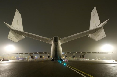 Post amazingly cool pictures of aircraft (Volume 2) - Page 182 - Boats, Planes & Trains - PistonHeads - The image captures a moment at an airport runway where a large, white commercial airplane is parked. The airplane is surrounded by a darkness, with its powerful lights on, creating a stark contrast against the sky. The foggy runway hints at the presence of a runway light, guiding the aircraft. Slightly above the airplane, smaller lights from other vehicles and airport equipment can be seen, adding to the bustling airport atmosphere.