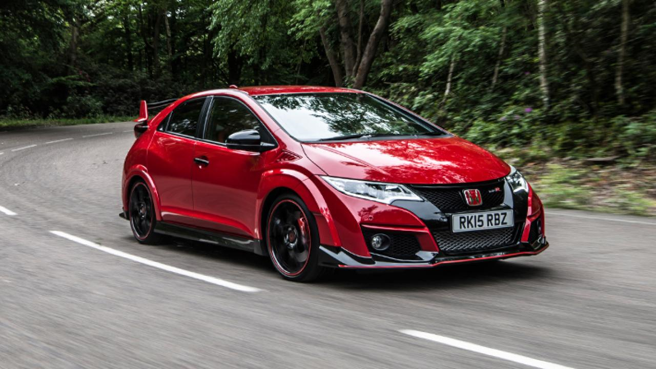 Best looking modern hot/warm hatch - Page 8 - General Gassing - PistonHeads - The image portrays an adventurous scene of a red Honda RK5 RS sportscar in motion on a curvy paved road. The car, with its distinctive red paint and black roof spoiler, is sharply angled, indicating it's making a turn on the right side of the road. The setting is a scenic rural area, characterized by a wooded area and lush greenery, which adds to the sense of speed and adventure. The image captures the car's dynamic nature as it maneuvers along the road, ready to tackle the twists and turns that lie ahead.