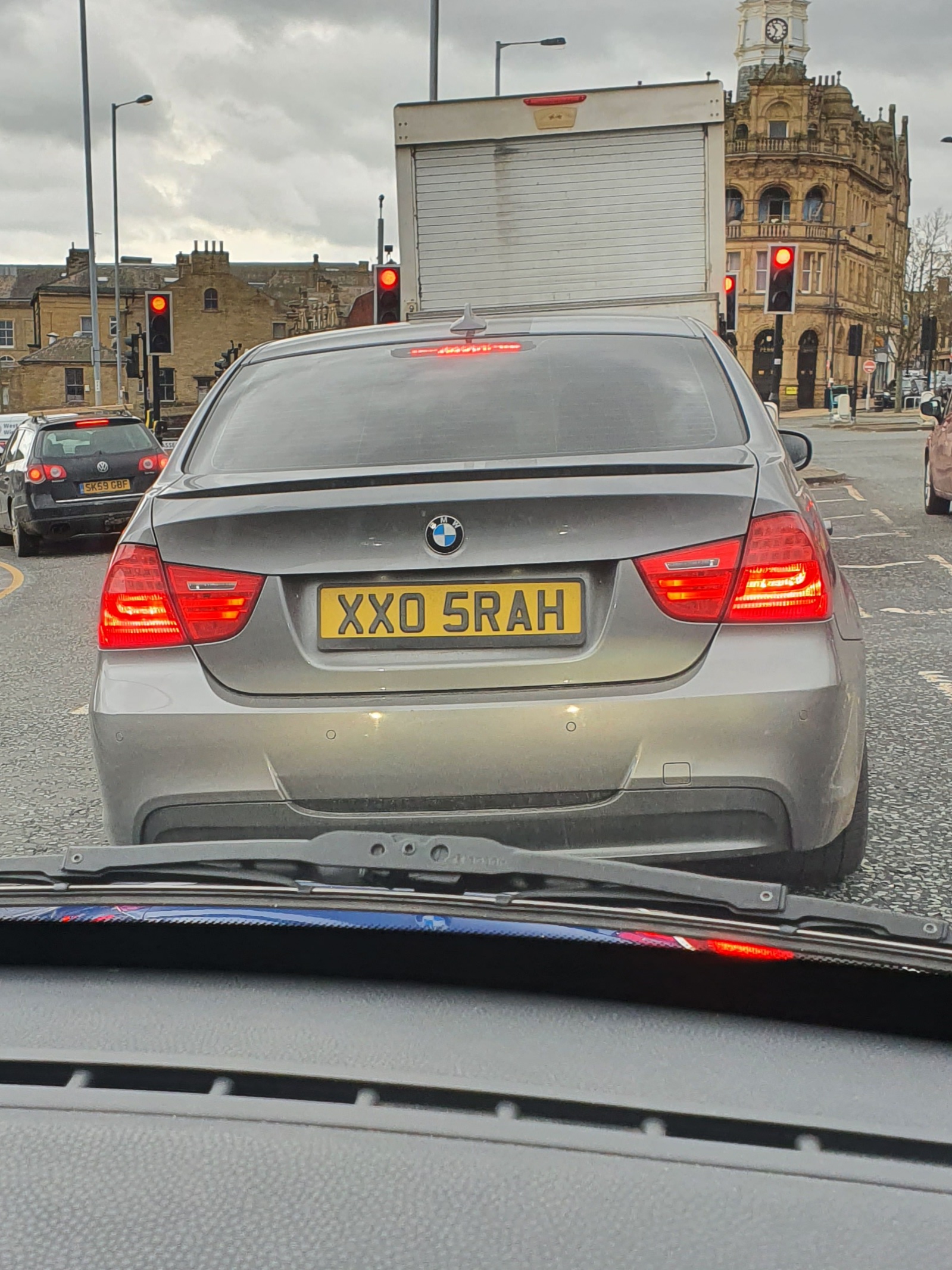 What C124PPY personalised plates have you seen? V01. 3 - Page 189 - General Gassing - PistonHeads UK - The image captures a scene on a city street. Dominating the scene is a silver BMW car, parked on the side of the road. A black license plate is prominently displayed on the car. The vehicle is situated on a sidewalk next to a traffic light, which is currently red. In the background, there's a large truck passing by and a building that appears to be a pub or restaurant. The overall scene suggests an urban environment with typical city elements like vehicles and infrastructure.