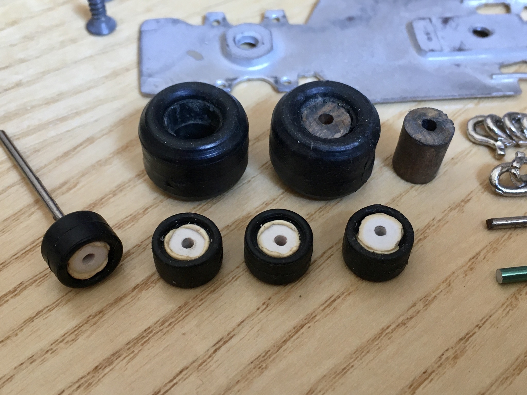 A wooden table topped with lots of clutter - Pistonheads - The image shows a collection of small black parts arranged on a flat surface. Some of these parts appear to be circular and have metal or plastic rings around them, which could suggest they are intended for assembly into larger structures. There are also a few nuts and bolts mixed in with the parts. In the top right corner, there is a metal key component, suggesting that some of these pieces might be related to key assembly. The image has a clear focus on the items, likely indicating an ongoing crafting or repair task.