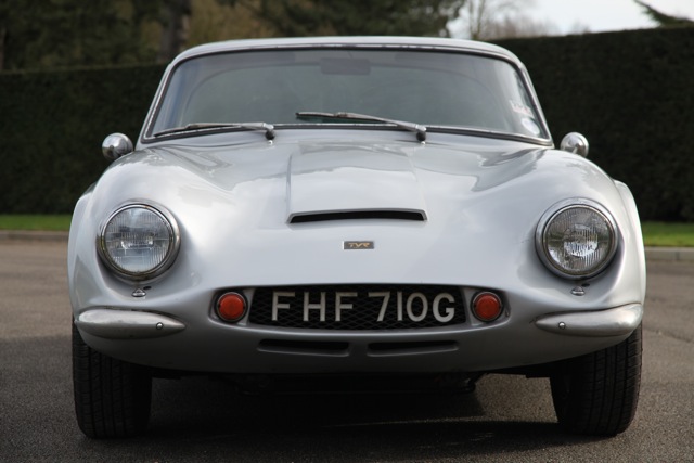 Early TVR Pictures - Page 35 - Classics - PistonHeads - The image features a white sports car parked on a paved surface, possibly a driveway or street. The car has a distinct design with a coupe body style and a long-hood, short-deck silhouette. The license plate reads "FH710G," and the car's overall condition appears to be in good order, possibly indicating it is well-maintained or restored. The background is slightly blurred but shows a blend of greenery and a structural background that could be part of a fence or wall.