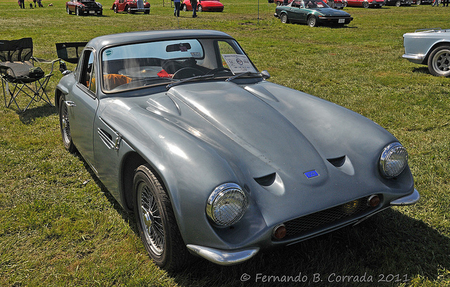 Early TVR Pictures - Page 11 - Classics - PistonHeads - The image showcases a classic car show in an open field. The main focus is a well-restored vintage gray car with white lights, chrome bumpers, and twin headlights. This beautiful vintage vehicle is parked alongside other antique cars that share the greenery of the field as a backdrop. The arrangement of the cars in a circle creates an atmosphere of camaraderie and shared appreciation for vintage vehicles.