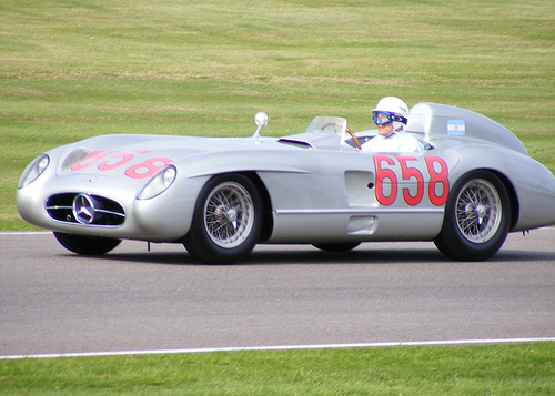 Pistonheads - The image captures an intense moment at a vintage race car competition. The car, with the number 658 prominently displayed, is a state-of-the-art vintage racer designed to resemble a Formula 1 car. The driver, dressed in full racing gear with a matching white helmet, is stylishly leaning into the left turn of the race track, embodying the thrill and speed of the sport. The car and driver are set against a backdrop of a lush green grass course, adding a touch of nature to the otherwise high-tech scene.