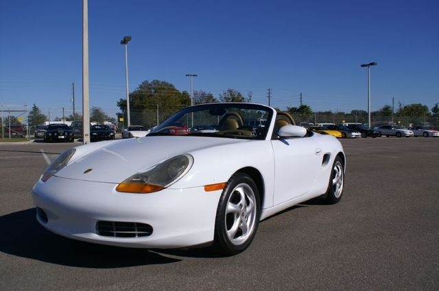 Boxster GTS air intakes... - Page 1 - Boxster/Cayman - PistonHeads - In the image, a white convertible sports car is parked in an empty parking lot. The car, with its top down, is the focal point of the image. The parking lot is surrounded by a fence, and there are various vehicles present, creating a contrast with the sports car. The convertible is parked under a few street lights, casting a soft glow on the car. The colors in the image are quite vibrant, with the white of the car standing out against the pavement, and the blue of the sky building a peaceful backdrop for the scene.