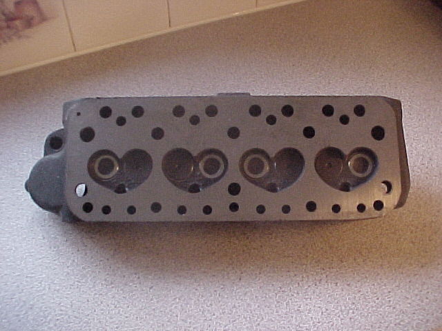 Pistonheads Purchase Advice - The image shows a metallic engine block placed on a countertop. It has a series of holes and protrusions, resembling a valve cover or a similar mechanical part. The part has a grid-like pattern, with alternating rings and smaller circles, suggesting it might be part of a complex engine. The surrounding surface is textured, possibly made of laminate or similar material, and appears to be a kitchen or a similar indoor space. The focus of the image is on the engine part itself, highlighting its structure and details with contrasting colors.