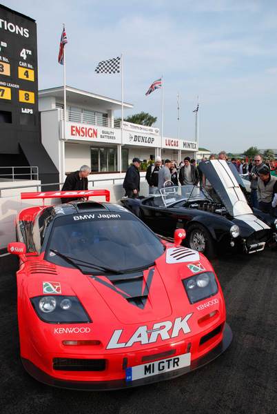 Supercar Sunday Pistonheads - The image showcases a public race track, where the main focus is on two striking sports cars. One car is a bright red Ferrari, boasting a sleek aerodynamic design, while the other is a black Bugatti, known for its speed and luxury. Both are prominently labeled "LARK" with the younger driver in the intersection, appearing ready for action. The crowd gathered watches and anticipates the event, adding to the excitement of the scene.