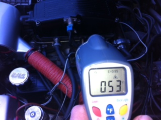 cooler air to the filter/airflow meter - Page 1 - Wedges - PistonHeads - The image shows a hand holding a digital display device, possibly a multimeter or a diagnostic tool, in front of an automotive engine. The device is displaying a reading, suggesting that it's measuring something related to the engine. The engine features various mechanical and electrical components, including wiring and a visible coolant level. The device is being used to check or monitor one of the engine's functions.