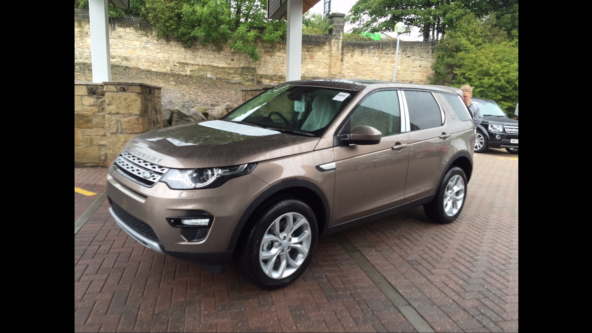 show us your land rover - Page 61 - Land Rover - PistonHeads - The image shows a silver-colored SUV parked on a brick pavement. It appears to be a luxurious vehicle, possibly an SUV or crossover, with a sleek and modern design. The vehicle is in the foreground, presented from a three-quarter angle, giving a clear view of its side profile. There are trees and plants in a kind of courtyard or garden setting in the background. On the driver's side of the vehicle, a single visible sticker adorns the windshield. The overall mood of the image is serene and somewhat candid, capturing a moment of calm urban setting.