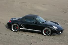 Pistonheads - The image depicts a black Porsche sports car parked on asphalt. It's an overhead shot that captures the car's sleek form and the details of its design, including the air intakes, rear spoiler, and alloy wheels. The vehicle appears to be new and in excellent condition, adding to its striking and powerful presence. There are no visible texts or distinctive markings on the car, and the scene is otherwise unadorned, suggesting a clear focus on the vehicle.