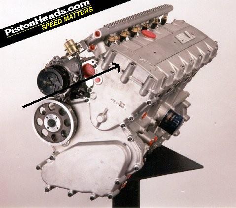 Head Pictures - Page 1 - Speed Six Engine - PistonHeads - The image presents a detailed view of a car engine from the side, revealing its intricate components. The engine is housed within a silver casing and complex mechanical parts are visible, suggesting a high-performance or racing engine. The engine has various plugs in different colors and sizes, which might be for gauging engine performance or modifying specific parts. This particular image is overlaid with a watermark that reads "PistonHeads.com," indicating the source or context of the photograph. The image is clear and well-lit, providing a comprehensive look at the engine's structure and design.