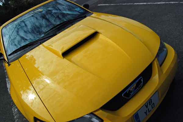 A red piece of luggage sitting on top of a wooden floor - Pistonheads - The image shows a bright yellow sports car, viewed from a slightly upward angle that emphasizes its curved hood and sleek lines. The car appears to be stationed on a road or street, as suggested by the urban setting and the presence of multiple lanes and markings. The vehicle's front grille is manufactured with a combination of large vents and smaller grills, typical of high-performance models. The overall condition of the car seems to be well-maintained, as there are no visible signs of damage or wear.