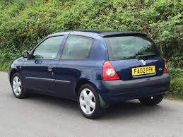 On the hunt for a Dark Blue MKII Clio - Farnborough - Page 1 - Thames Valley & Surrey - PistonHeads - The image features a small hatchback car parked on a pavement road near lush green foliage. The car is primarily blue, with a small red taillight characteristic of French license plates. The vehicle's side and back windows provide visibility to the inside.