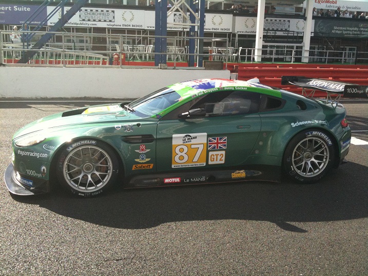 Series Silverstone Pistonheads Sept - The image depicts a racing car on a track. The car is predominantly green with accents of white, blue, and red. It is adorned with various logos and number Eighty Seven (87). The tires are made by Michelin, as indicated on side of car. The car appears well-maintained, suggesting it is prepared for a competitive event. The surrounding environment suggests it's an outdoor racing circuit, with safety barriers and white fences lining the track.