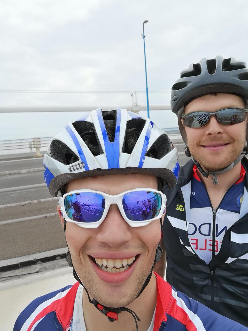 The "Photos From Today's Ride" thread... - Page 356 - Pedal Powered - PistonHeads - The image captures a moment between two individuals possibly after a bike ride. The person on the left is donned in a blue and white helmet with reflective blue and white sunglasses, looking directly at the camera with a bright smile. To the right, another person is also wearing a helmet and sunglasses, theirs black with a white frame, and their smile is directed slightly towards the left. Both are standing in front of a walkway or railing, creating a separation between the background and the people in the foreground.