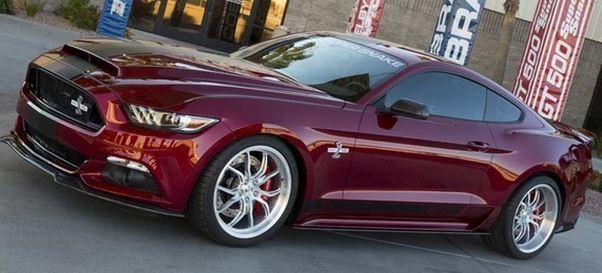 So who has ordered the new S550 Mustang? - Page 51 - Mustangs - PistonHeads - The image shows a close-up of a shiny, metallic red Mustang car, which is parked on a road alongside a curb. The car features prominently visible design elements such as the name "BRONCO" on the side and "KRTSIC 700" also on the side. The car's wheels are five-spoke alloys, and there is a noticeable shine on the car's exterior. The setting appears to be urban or semi-urban with paved roads and some foliage in the background.