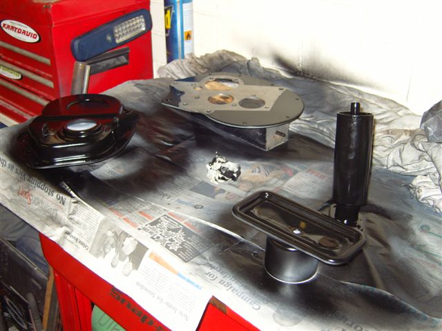 pics - Page 1 - Classic Minis - PistonHeads - This is a photograph featuring an array of car parts and accessories laid out on a workspace. The scene includes mechanical components such as what appears to be a hubcap, brake discs, and possibly a part of a wheel well. There are also small alcohol-based bottles, possibly containing cleaning solutions, suggestive of an automotive maintenance or repair context. The setting seems to be a garage or workshop area, with an array of tools and parts scattered about. The image has a qualitative, informal quality, and the lighting is not very soft, which indicates it might have been taken during a working process rather than as a finished photograph with professional lighting.