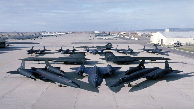 Just awesome vehicle-related images. - Page 6 - General Gassing - PistonHeads - The image shows a collection of military fighter jets parked on a concrete tarmac. The jets are arranged in two neat rows, with their noses pointing towards the center of the image. Each jet is painted in a dark color and is, visibly, in excellent condition. The sky in the background is slightly hazy, creating a muted backdrop that highlights the jets. There are no people visible in this scene.