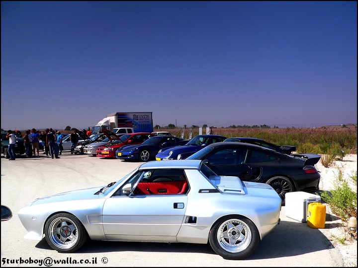 Pictures of decently Modified cars  - Page 129 - General Gassing - PistonHeads - The image depicts a vibrant scene of a car show on what appears to be a sunny day. A variety of cars are parked in parallel rows on a paved surface against a backdrop of a broad, open sky. The cars range from classic models with shiny, polished surfaces to modern sports cars, showcasing a mix of styles and colors. Some cars are closer to the viewer, while others are parked further back, creating a sense of depth in the image. Several people can be seen casually strolling through the scene, adding a human element to the display. The ground is a light color, possibly asphalt, and the cars are arranged in such a way that they create a contrast with the vast expanse of open sky above.