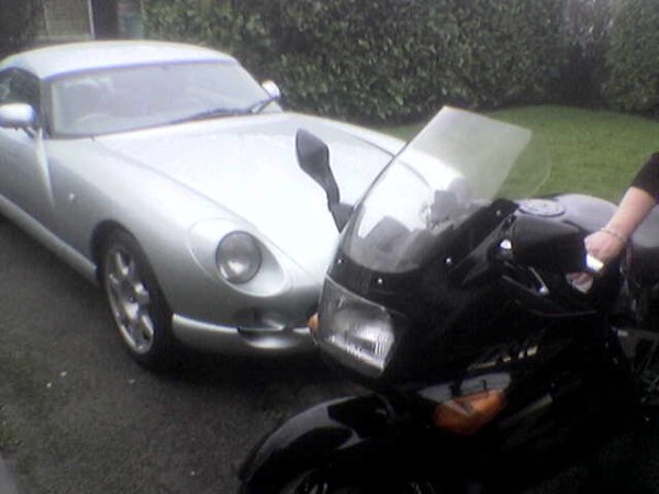 Show us your Daily driver, and Weekend Toy(s)!!! - Page 3 - Readers' Cars - PistonHeads - The image shows two vehicles on a paved surface, with an individual to the right side of the image. On the left is a classic, silver-colored convertible car with a sleek design, and on the right is a black motorcycle, possibly a BMW due to its distinctive round headlight. The individual appears to be interacting or closely associated with both vehicles, possibly the owner of the vintage car. The background is slightly blurred, emphasizing the vehicles in the foreground.