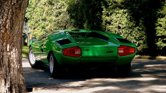 Countach  - Page 7 - Lamborghini Classics - PistonHeads - The image features an unusual sports car parked among large, thick trees. The vehicle's most striking element is its vibrant, lime green color, which is bright and eye-catching. It appears to be a single-seater, with only one passenger seat visible in the image. The descriptive background suggests that the driver's side is parked next to a tree.