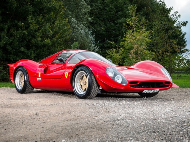 "Noble Ferrari P4" sold - Page 1 - Noble - PistonHeads - The image features a bright red Ferrari sports car parked on a gravel surface. The car is sleek and streamlined, with its distinctive short nose and long tail design typical of Ferrari's monoposto supercars. The vehicle is oriented towards the left side of the photo, with its front portion slightly angled towards the viewer. A clear blue sky forms the backdrop, enhancing the vibrant color of the Ferrari. The car's design, combined with the contrasting background, gives the image a dynamic and visually appealing perspective.