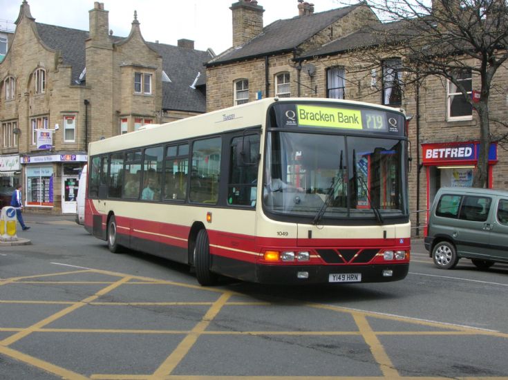 Converting a bus into a motorhome - Page 1 - Tents, Caravans & Motorhomes - PistonHeads - The image features a city street scene where a public transit bus is driving on the asphalt. The bus is large, with a predominantly red and white color scheme. On the front of the bus, there are signs and writings, although specific details about the bus route or destination are not clear. To the right and behind the bus, there's a small van slower in motion. On the left side of the street, there are parked cars, and a man is visible walking on the pavement. In the background, there are houses and a building on the right side. This image captures a typical urban environment, showcasing elements of transportation, architecture, and daily life.