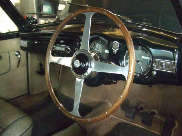 Pistonheads Dear Dtype - The image showcases the interior of a vintage car, focusing on the steering wheel and the dashboard. The steering wheel is prominently positioned, featuring a wooden rim and a brushed metal centerpiece. The dashboard, though partially visible, houses several gauges, providing a glimpse into the vehicle's functionality. The black and white color scheme evokes a sense of nostalgia, reminiscent of classic cars. The left side of the image provides a hint at the car's interior, suggesting leather seats. The overall composition of the image gives a feel of the car's historic design.