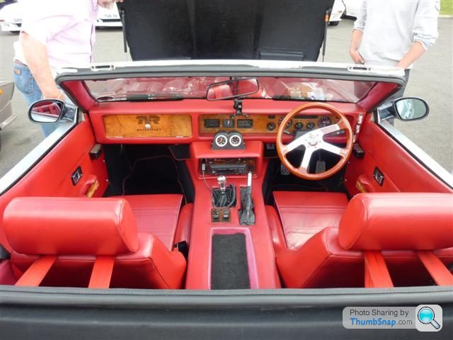 Wedge Interior Pistonheads Remodel Retrim Comments - The image showcases a striking classic red convertible sports car sitting on a street next to another vehicle. The car's interior is prominently displayed, featuring a wooden dash panel, leather seats, and a traditional steering wheel. The vehicle appears well-maintained, with indications of mechanical work possibly being performed, as suggested by some tools visible in the trunk. Additionally, the picture includes a watermark, suggesting it may originate from a photography sharing platform.