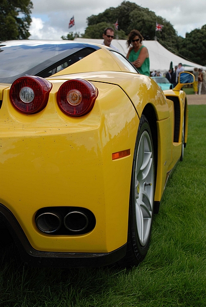 GRRC Lunch Club - Page 1 - Goodwood Events - PistonHeads - The image captures a vibrant scene at a car show. Dominating the frame is a striking yellow Lamborghini, its back end facing the camera. The car's exhaust pipes are prominently displayed, adding to its appeal. Its red taillights also stand out, complementing the overall brightness of the vehicle.

In the background, there are a few people, adding a sense of scale to the image. They appear to be admiring the car, likely taking in its sleek design and bold color. The contrast between the people in the distance and the vivid yellow of the Lamborghini makes the car the clear focal point of this image.