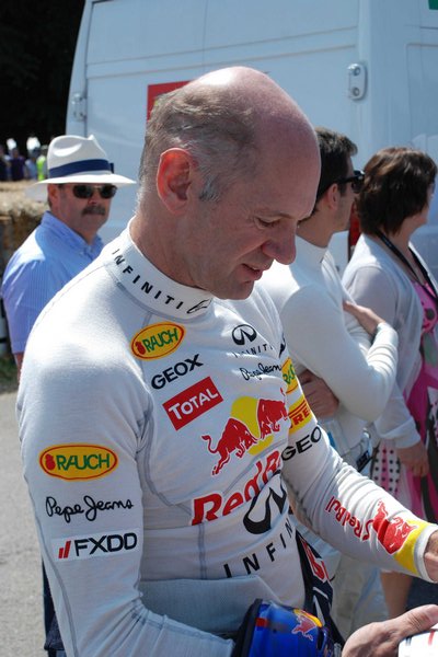 Post your Pics, Celebrities at  FOS 2011 - Page 1 - Goodwood Events - PistonHeads - This image captures a moment at a race event. The focus is on a man, likely a race driver, dressed in a white racing suit with various logos on it. The suit is adorned with sponsor logos, signifying his involvement in the sport. In the background, other individuals can be seen, some wearing similar white suits and others in casual attire. The setting appears to be a racetrack, as indicated by the presence of a truck and a race helmet in the scene. The overall atmosphere is one of anticipation, possibly minutes before the start of a race.