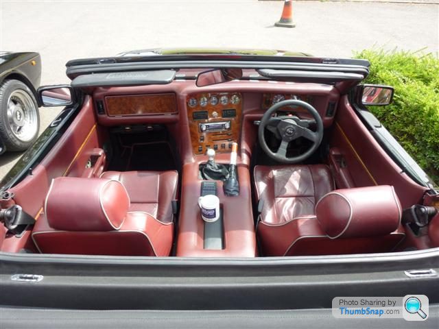 Pistonheads - The image showcases the interior of a convertible car. The car's interior is luxurious, featuring a high-quality leather seat and upholstery, suggesting it's a premium vehicle. The center console, which houses essential controls for the vehicle, is also adorned with leather, with a multitude of controls such as the engine start button, cruise control, and center touchscreen visible. A cup holder is also placed on the console, behind the center armrest. The overall impression is one of opulence and comfort.