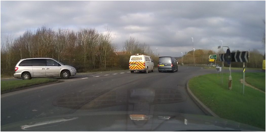 One single thing that makes you think "knob" Vol 2 - Page 367 - General Gassing - PistonHeads - The image shows a busy road with several cars and a van. There are two black cars, one of them is directly in front of a silver van, possibly indicating heavy traffic or a traffic jam. Another car is visible on the left side of the image, parked or stopped. The road seems to be leading towards a traffic light which is visible in the upper right corner of the image. The sky above appears overcast.