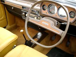 A motorcycle parked in front of a mirror - Pistonheads - The image showcases the interior of a vintage car, specifically focusing on the steering wheel. The steering wheel is large and round, with a chrome center that contrasts with the dark woodgrain pattern that encircles it. The word "Formula" is printed in bold letters across the bottom of the wheel, suggesting a connection to racing or high performance. The driver's side is visible, and the dashboard has silver gauges, which are a typical feature in many classic cars. The car has a seafoam color scheme, adding to its vintage charm. The image is a close-up shot, allowing for a detailed view of the steering wheel and its design.