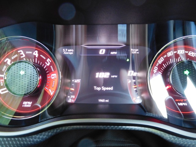 Hellcat good mpg...and not so good - Page 1 - Yank Motors - PistonHeads - The image presents a close-up view of a car's dashboard, specifically focusing on the speedometer and the digital dashboard display. The car's speedometer, a circular object, shows 5.7 mph in its center while the average speed is indicated as 182. The digital dashboard display indicates a top speed of 0 mph, a range of 102.300 mph, and a top speed of 0 mph. The dashboard contrasts the reds and whites of the speedometer with the black background and white letters.