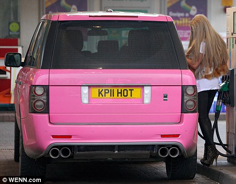 A red car parked in front of a red fire hydrant - Pistonheads - The photo features a bright pink compact car parked at a gas station. A female, possibly a teenager going by her fashion style, is seen standing just behind the rear of the car. She is holding a phone to her ear. At the gas pump, the car's tank appears to be empty. In the background, characteristic elements of a gas station can be seen, such as pumps and fuel logos on the wall.