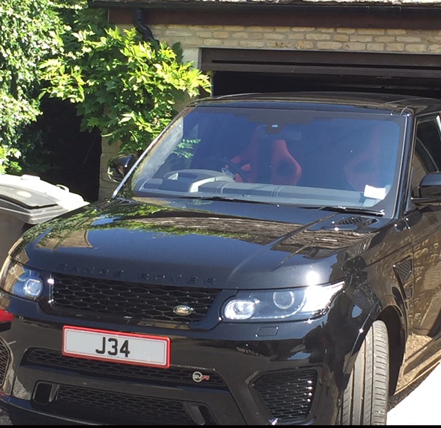 Real Good Number Plates vol 5 - Page 411 - General Gassing - PistonHeads - The image depicts a black Range Rover SUV parked in front of a garage with a person's reflection visible in the vehicle's side mirror. The garage entryway is open, and the interior light is on, illuminating the truck and the surrounding area. A small amount of luggage is visible beside the vehicle. The photo has a casual, candid quality to it, suggesting a moment captured without formal posing.