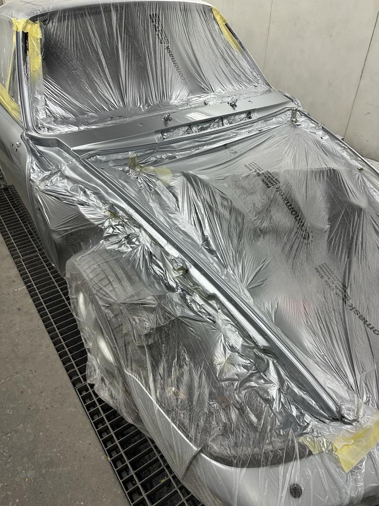 Pistonheads - This image shows a car in the process of being painted. The body of the car is covered with silver plastic, which serves as a barrier during the painting process to prevent overspray and maintain cleanliness on other parts of the vehicle. This type of setup suggests that the car is either being prepped for a new color or has just been painted and is now drying under this protective cover.