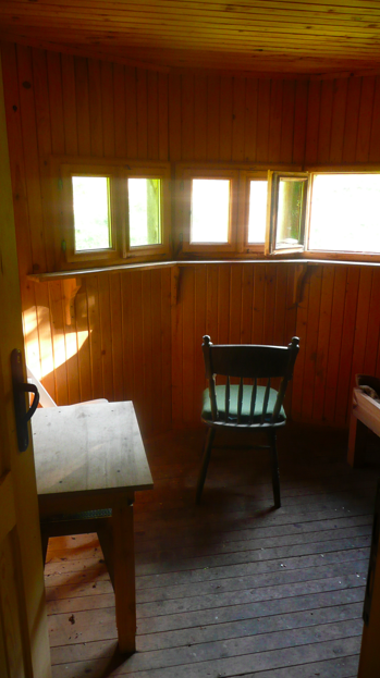 Little overnight trip to the Balkan range - Page 1 - Off Road - PistonHeads - The image showcases a rustic interior, likely of a wooden cabin or shed. In the center of the frame is a bench, made of wooden slats, accompanied by a simple, light-colored table. The bench is placed beside a high window with images of the outside environment, suggesting a cozy and secluded space. The floor beneath is adorned with weathered wooden planks, adding to the overall rustic ambiance. The table and bench form a homely setting, perhaps a reading nook or a quiet corner for rest. The walls are lined with a wooden wainscoting, and a door on the right completes the scene.