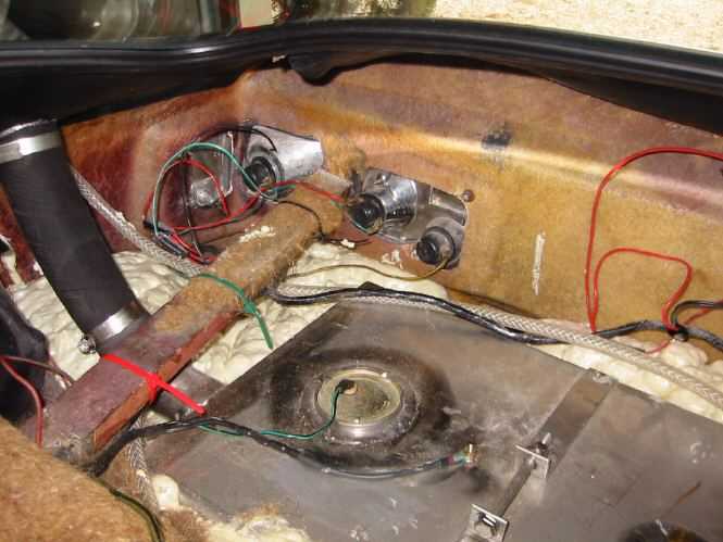 Fuel tank support and fixing for Vixen. - Page 1 - Classics - PistonHeads - The image shows the intricate inside of a vehicle, focusing on the engine compartment. Several wires and components are visible, with a combination of brown and black colors suggesting different materials and purposes. There appears to be a burnt part of a wire resembling a drip pan by the battery, implying some sort of mechanics. The overall setting suggests an automotive context, given the emphasis on engine related items.